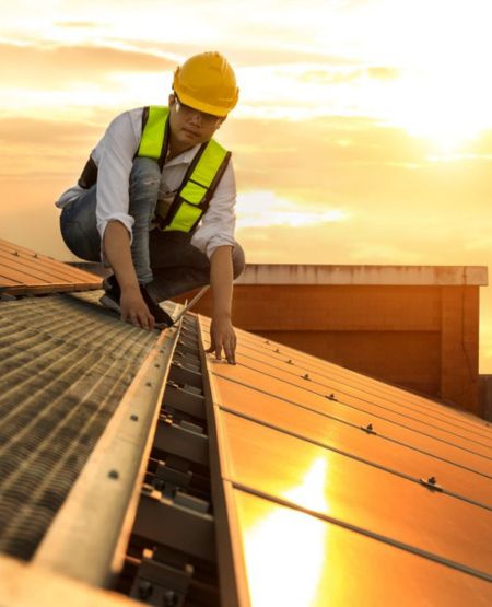 Installateur de panneaux solaires en sécurité sur un toit lors de l'installation